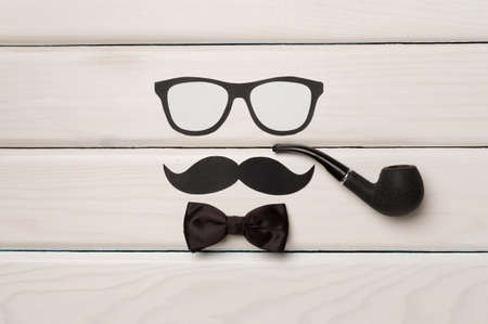 Glasses, mustache and bow tie on wooden background, top view. Happy Father's Day concept.の写真素材