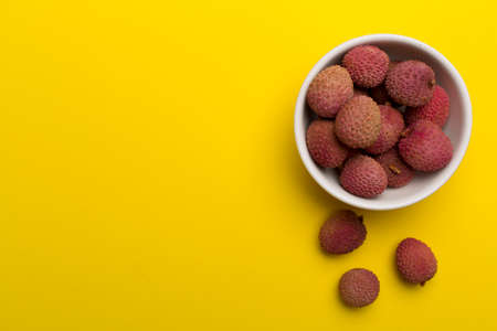 Lychee fruit in bowl on color background. Top view, copy space text.の写真素材