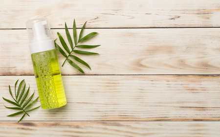 Foaming facial cleanser and cotton pads on wooden background, top view.の写真素材