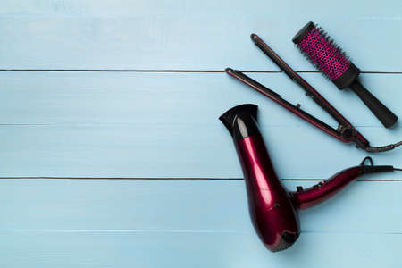 Hair dryer, straightener and brush on wooden background, top view.の写真素材