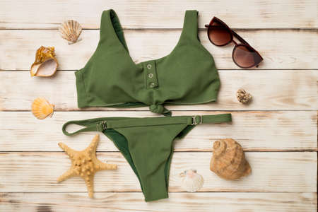 Beautiful green bikini on color wooden background, top view.の写真素材