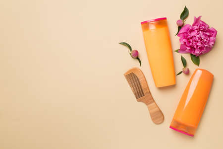 Shampoo and conditioner with peony flower and comb on color background, top view.の写真素材
