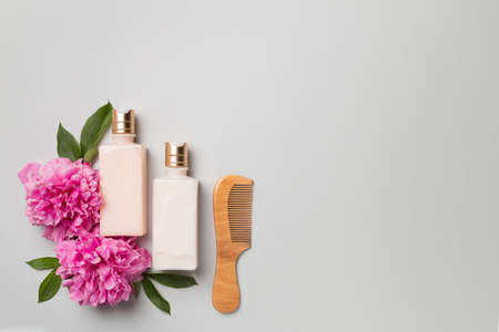 Shampoo and conditioner with peony flower and comb on color background, top view.の写真素材