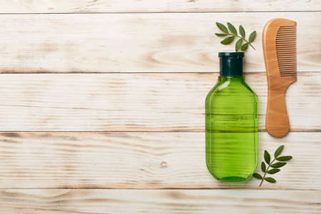 Shampoo with herbal extract and comb on wooden background, top view.の写真素材