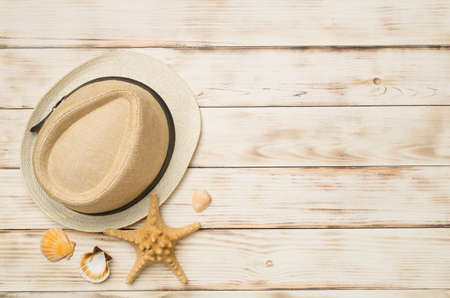 Wicker hat and seashells on wooden background, top view.の写真素材