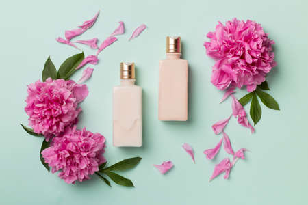 Flat lay composition with cosmetic bottles and peony flowers on color background, top view.の写真素材