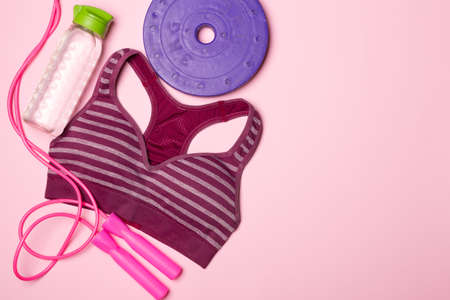 Flat lay of sport bra and sport equipment on color background.の写真素材