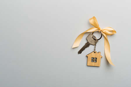 House key with golden bow on color background.の写真素材