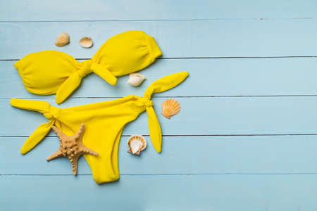 Beautiful yellow bikini on color wooden background, top view.の写真素材