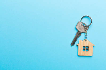 Keys with house-shaped keychain on color background.