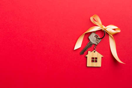 House key with golden bow on color background.