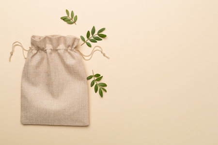Burlap eco sack with green leaves on color background, top view.の写真素材
