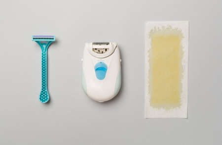 Wax strips, modern epilator and razor on color background, top view.の写真素材