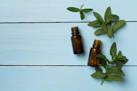 Melissa essential oil bottles on wooden background, top view.