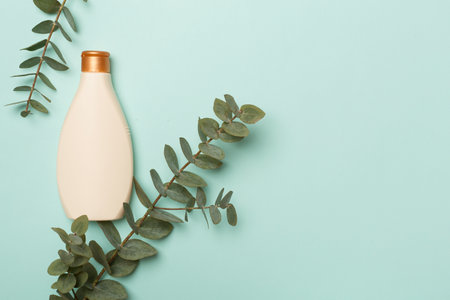 Cosmetic bottle with eucalyptus branch on color background, top view.の写真素材
