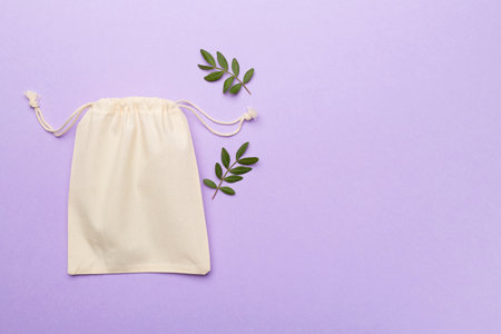 Small eco sack with green leaves on color background. Top view.の写真素材