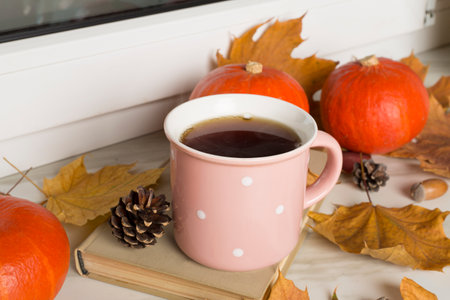 Cup of tea with pumpkins and autumn leaves on windowsill.の写真素材