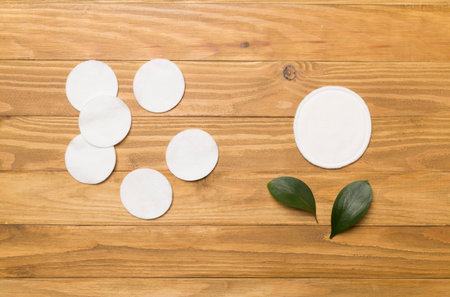 Reusable cotton pads with disposable ones on wooden background, top viewの写真素材