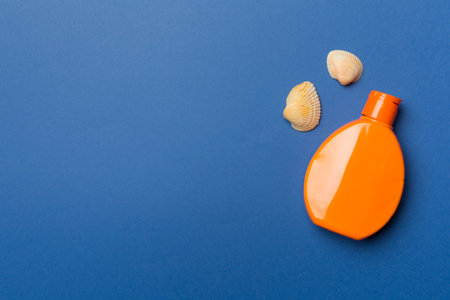 Bottle with sun protection cream and sea shells on color background, top view.の写真素材