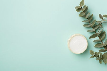 Cosmetic jar with eucalyptus branch on color background, top view.の写真素材