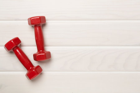 Red dumbbells on wooden background, top viewの写真素材