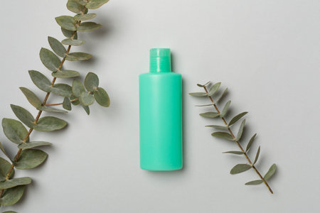 Cosmetic bottle with eucalyptus branch on color background, top view.の写真素材