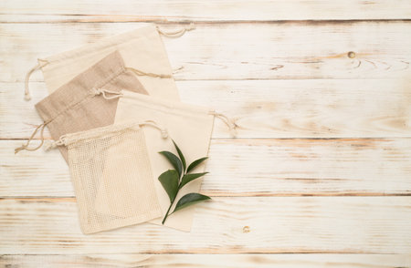 Small eco sacks with green leaves wooden on background. Top viewの写真素材