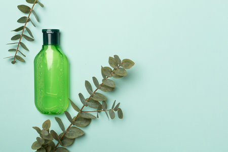 Cosmetic bottle with eucalyptus branch on color background, top view.の写真素材