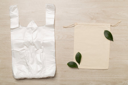 Plastic and fabric bag on wooden background, top view. Biodegradable products conceptの写真素材