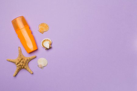 Bottle with sun protection cream and sea shells on color background, top view.の写真素材