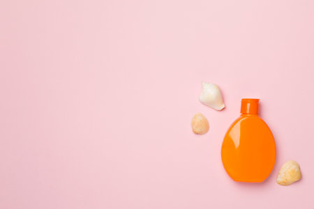 Bottle with sun protection cream and sea shells on color background, top view.の写真素材