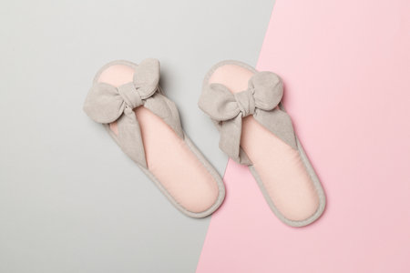 Soft pink slippers on color background, top view.