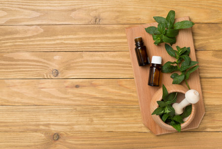 Melissa essential oil bottles with mortar pestle on wooden background, top view.の写真素材