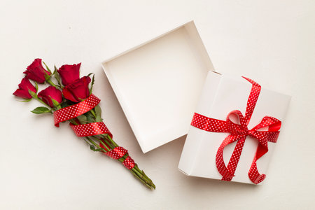 Open gift box with red roses on wooden background, top viewの写真素材