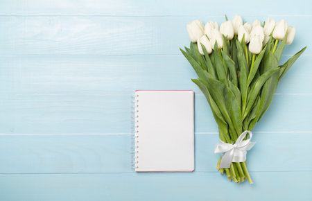 White tulip bouquet with notebook on wooden background, top viewの写真素材