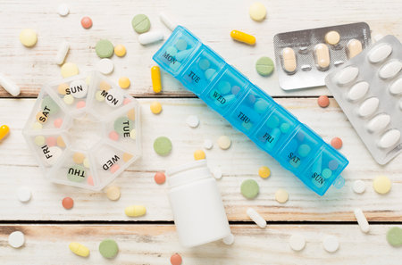 Daily pill organizer with medications on concrete background, top view