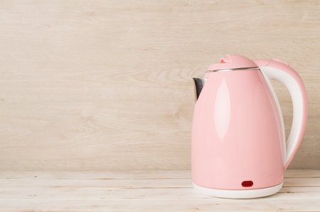 Modern electric pink kettle on wooden tableの写真素材