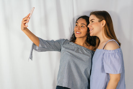 LATIN GIRL WITH CAUCASIAN GIRL WITH BLUE CLOTHES TAKING A SELFIE