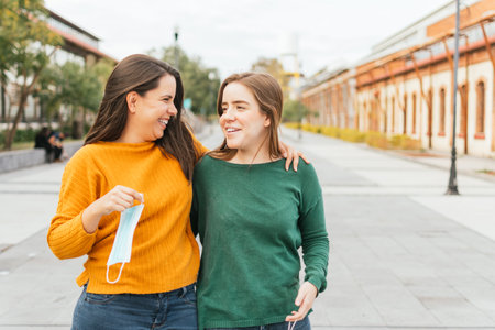 TWO CAUCASIAN WOMEN LAUGHING WITH A MASK IN THEIR HANDSの写真素材