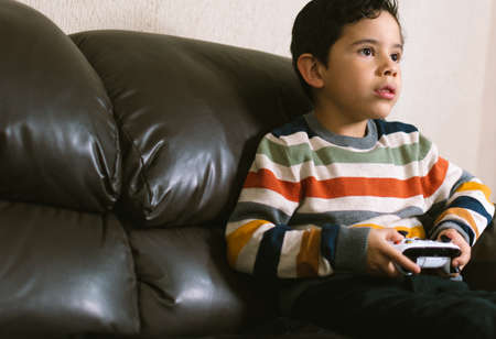 LATIN KID PLAYING VIDEO GAMES ON THE COUCHの写真素材