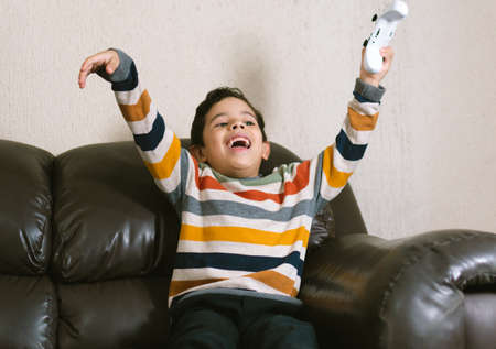 LATIN KID PLAYING VIDEO GAMES ON THE COUCH
