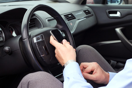 businwssman using  mobile smart phone while driving the car