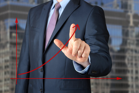 Bisinessman  ?? a modern suit Touching   a Graph by hand. Green background besideの写真素材