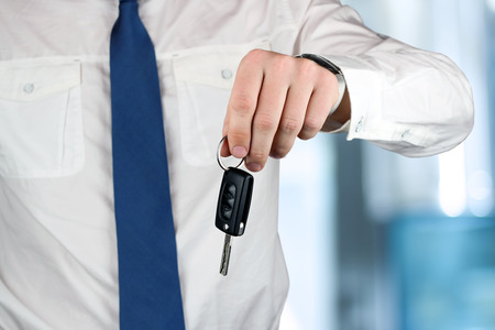 Young successful businessman offering a car key. Close-up of driverの写真素材