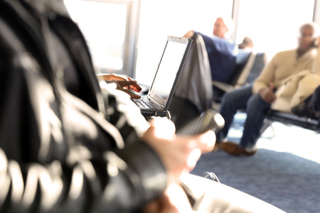 Passengers waiting at the airport/ Passengers using mobile phone and laptop