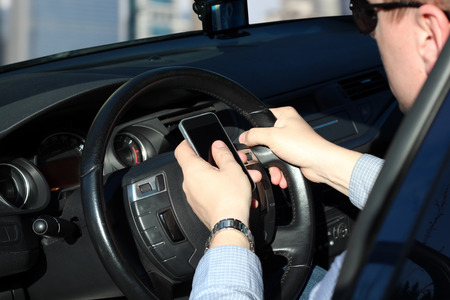 The businwssman using  mobile smart phone while driving the car