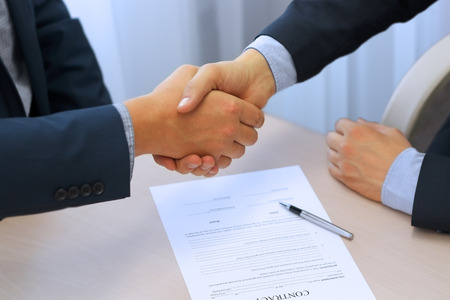Close-up image of a firm handshake between two colleagues after signing a contractの写真素材