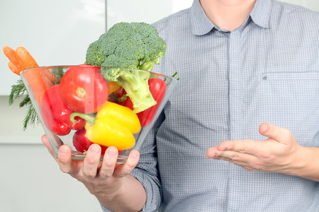 man holding glass dish with  fresh vegetables in the kitchenの写真素材