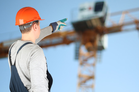 Worker in a construction site showing on a crane