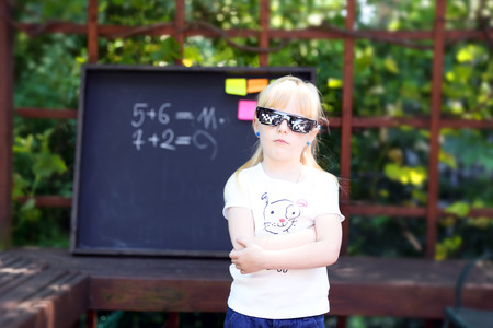 cute little girl with pixel glasses  standing ahead  blackboard